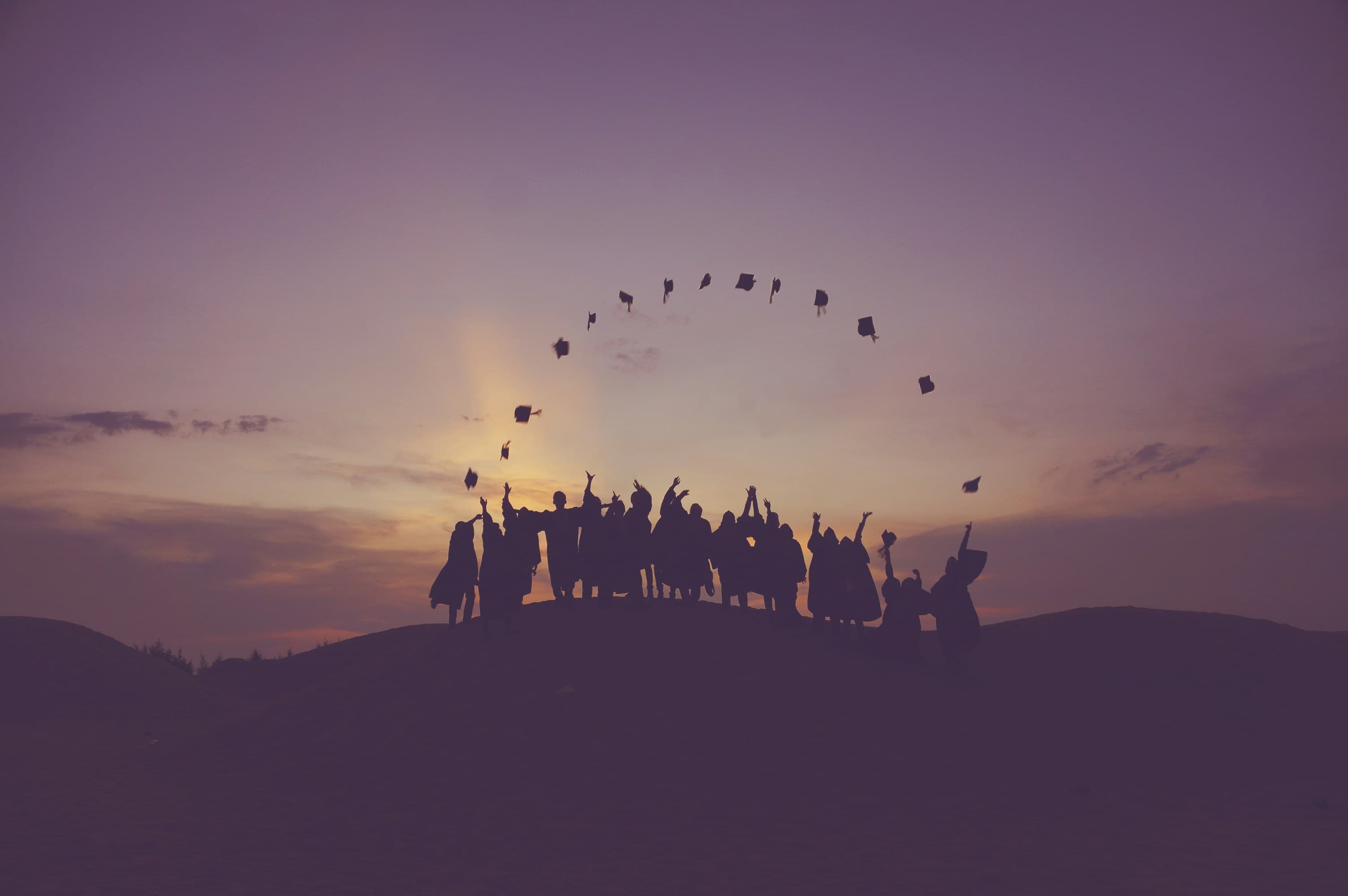 Groupe de diplômés qui sautent au coucher du soleil