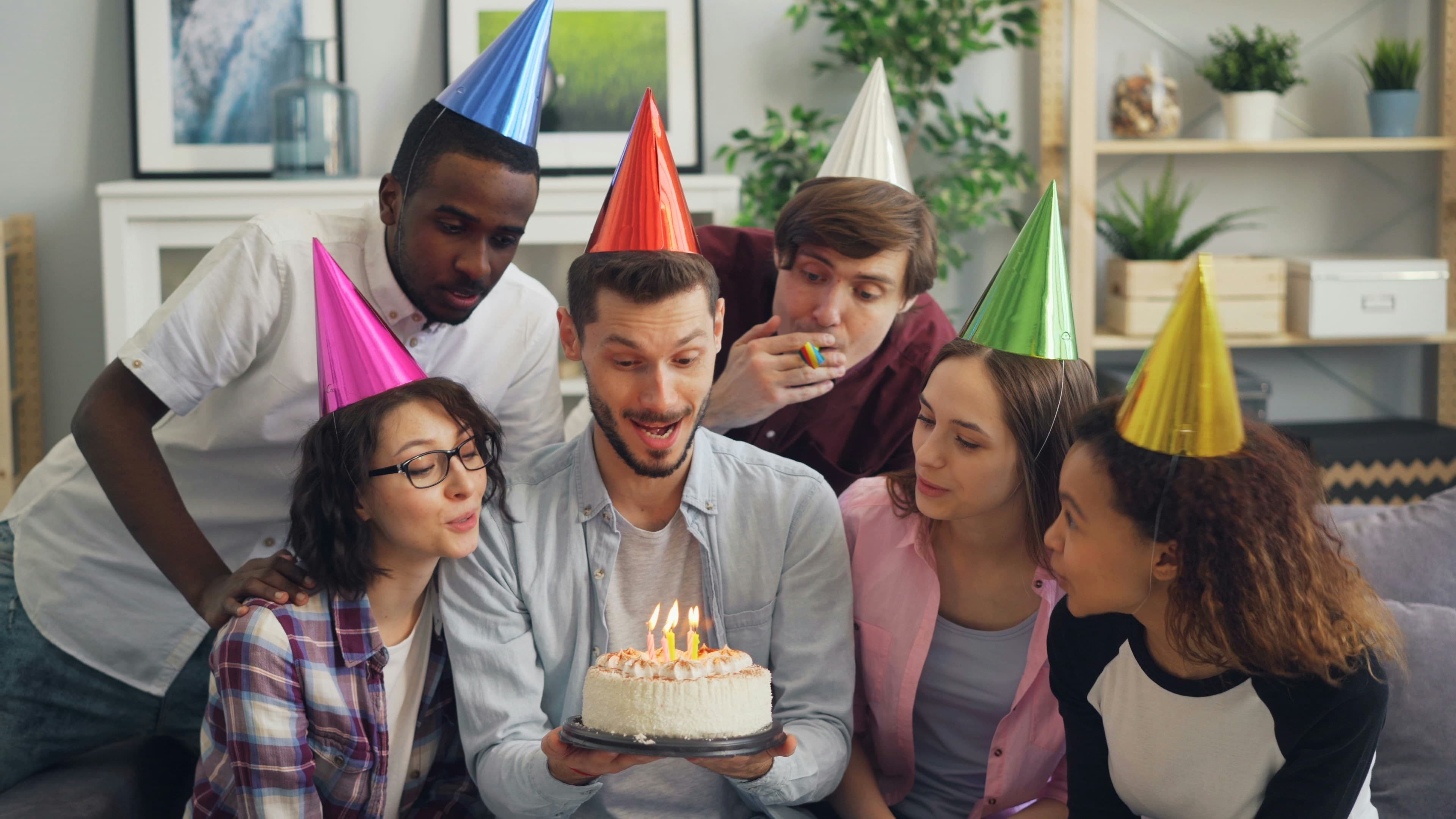 Amis en chapeaux de fête autour d'un gâteau