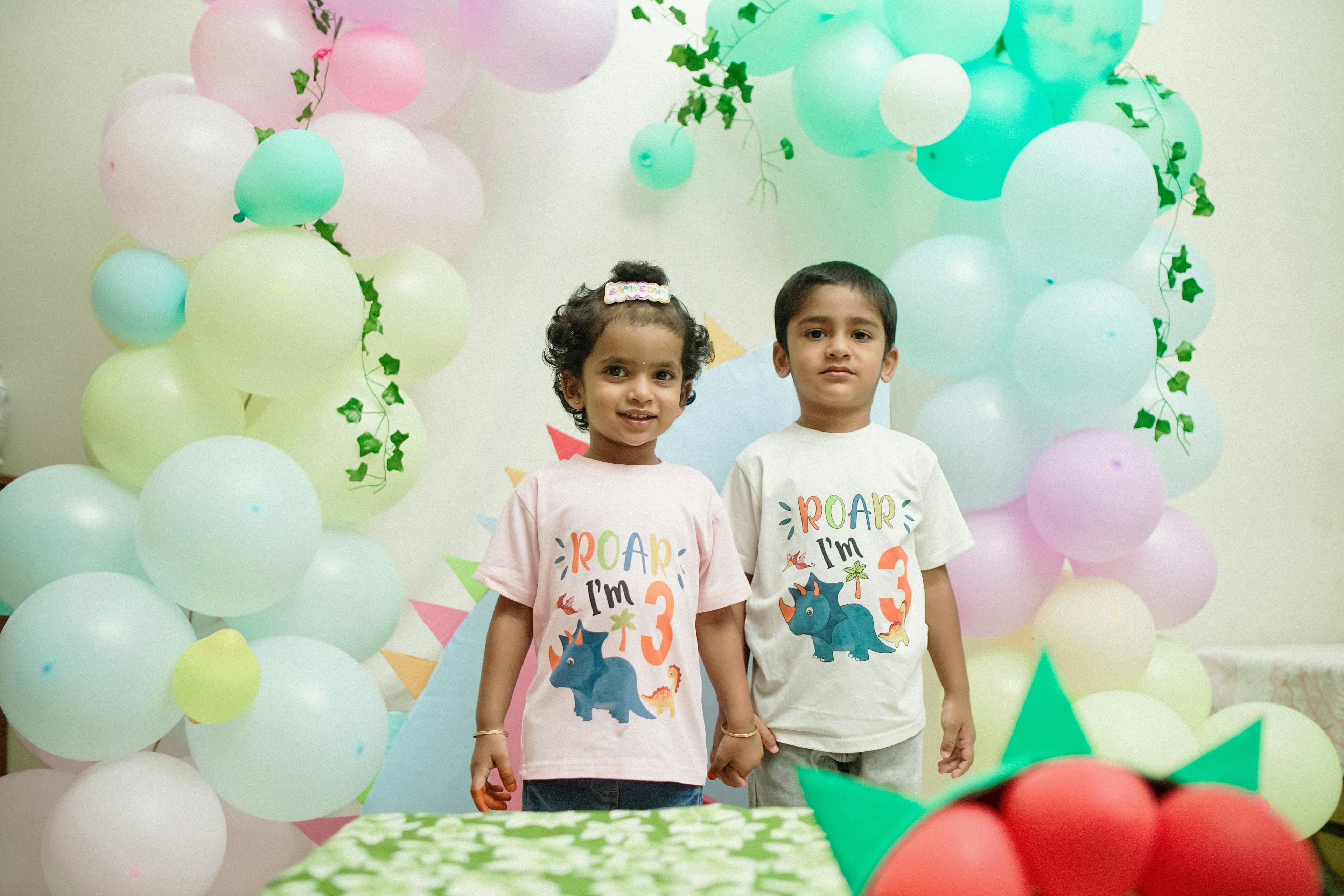 Enfants souriants devant une arche de ballons pastel